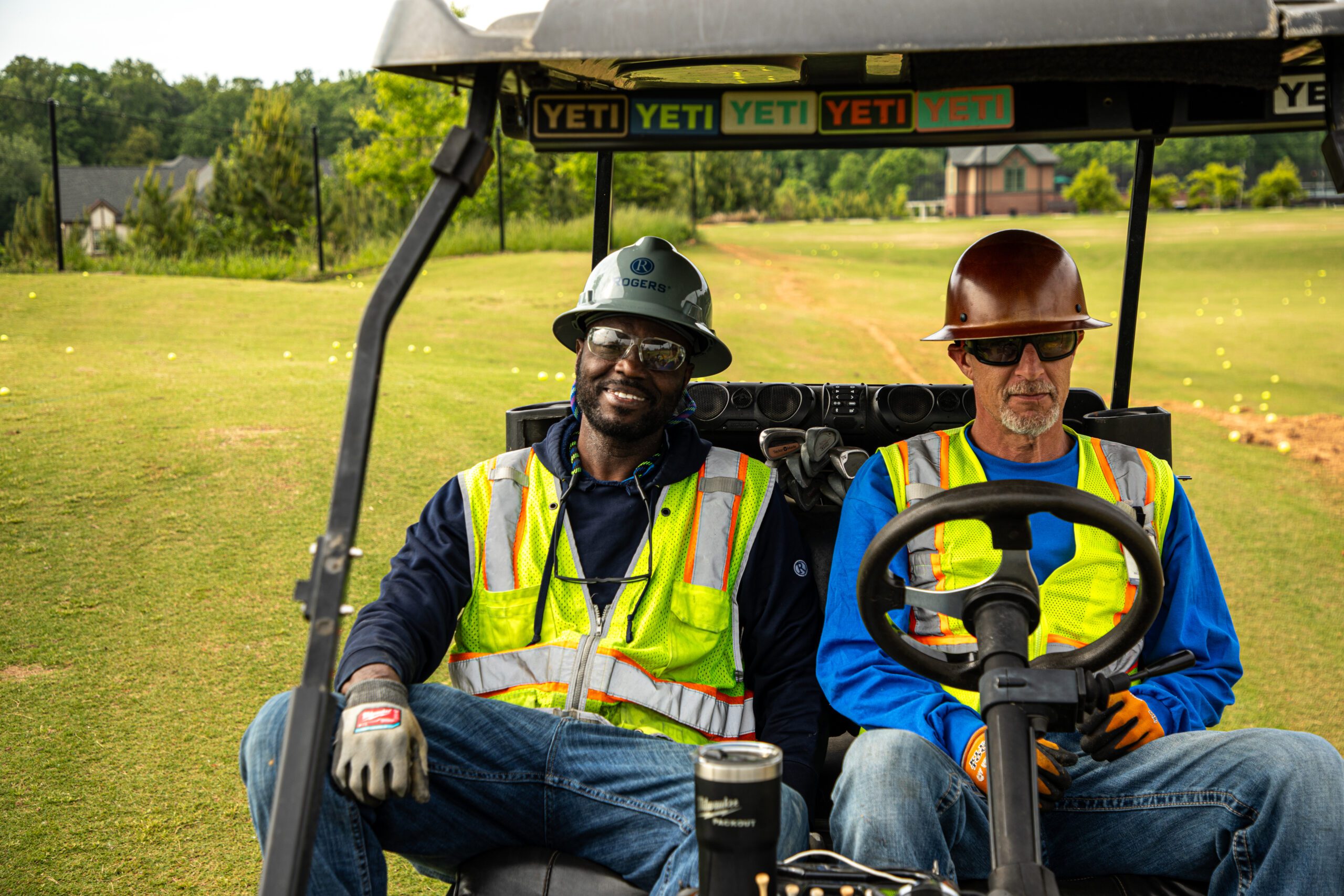 Two Rogers Electric technicians on project site in golf cart.