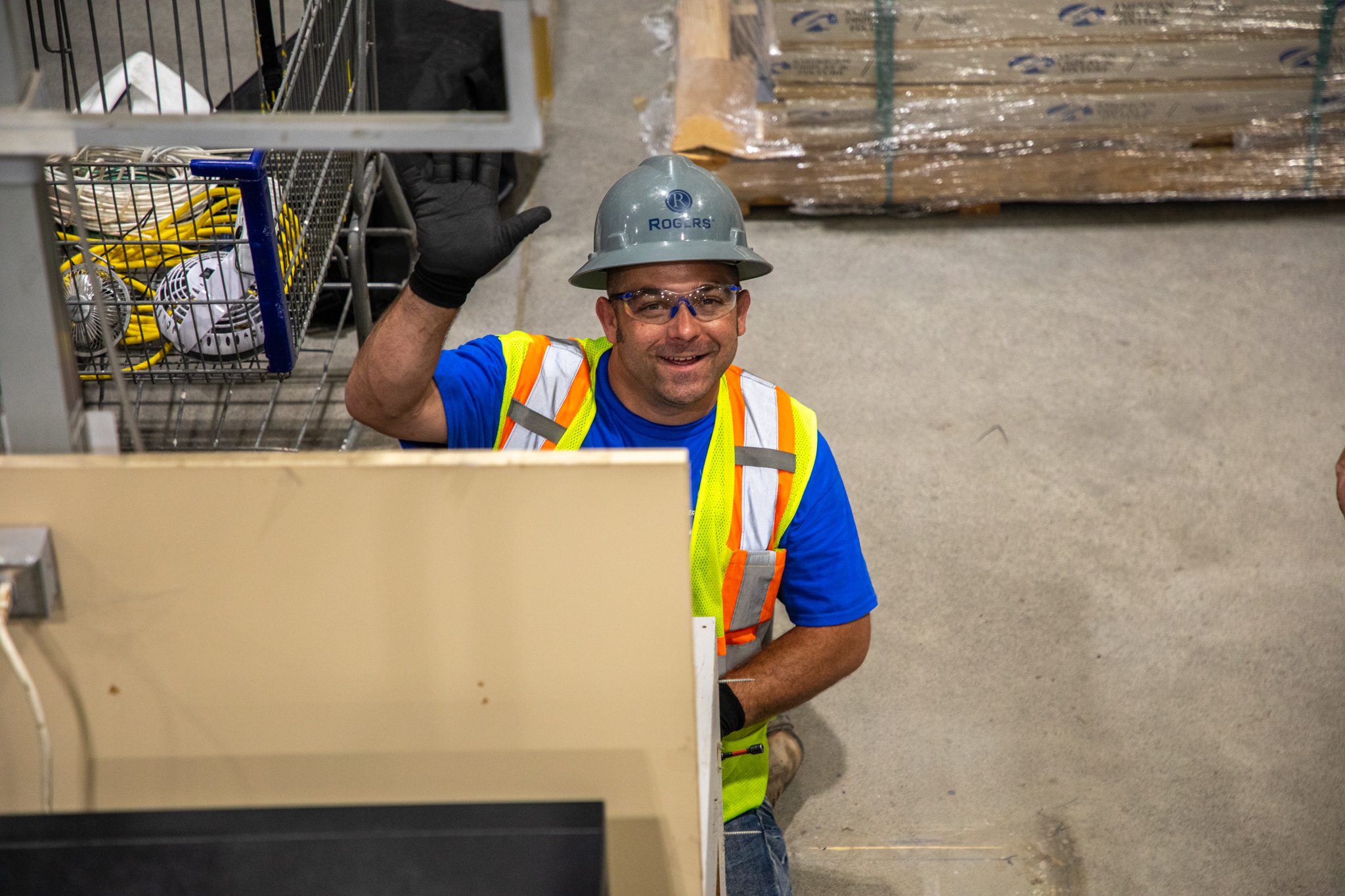 Technician waving as he works on new self-checkout.