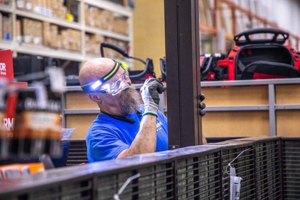 electrician with safety glasses, gloves, and headlamp looking at the inside of a pole inside a retail store