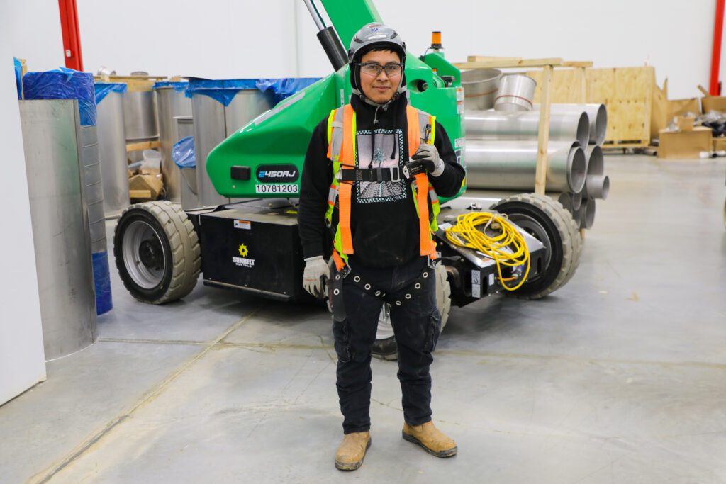 construction electrician smiling at the camera with his harness and safety gear on