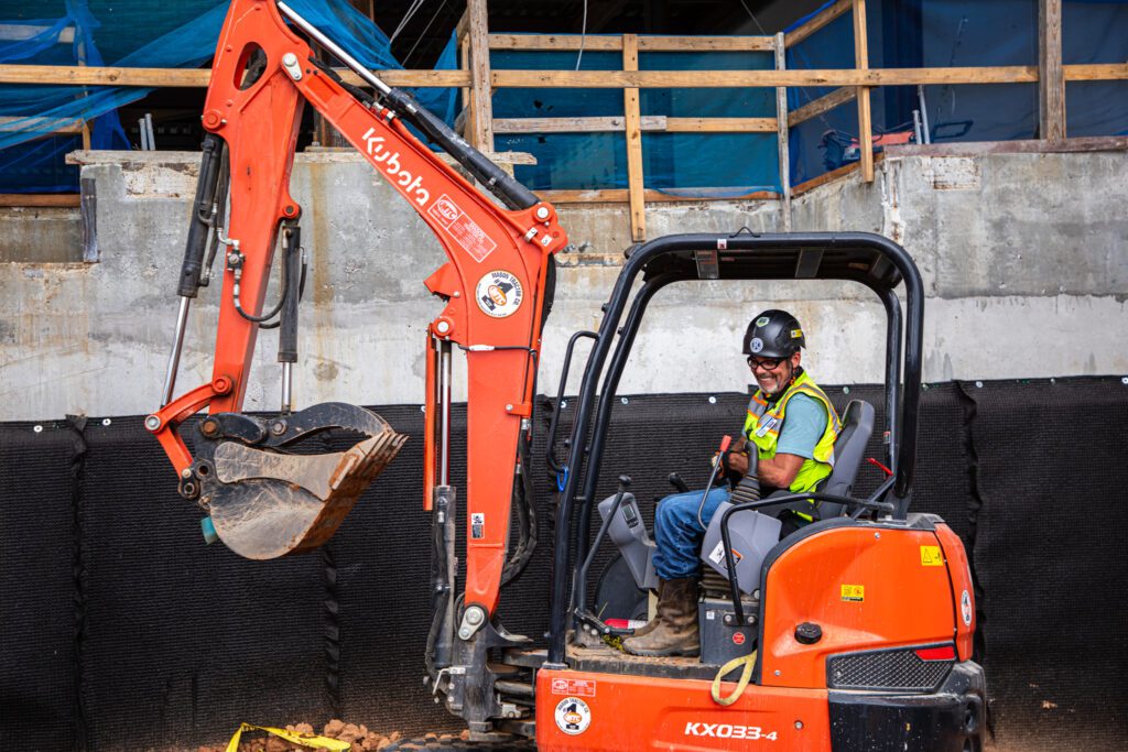 electrician with safety gear on controlling an orange loader