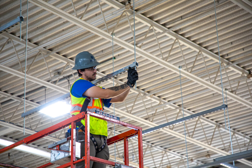 electrician putting in LED lights in ceiling wearing full PPE