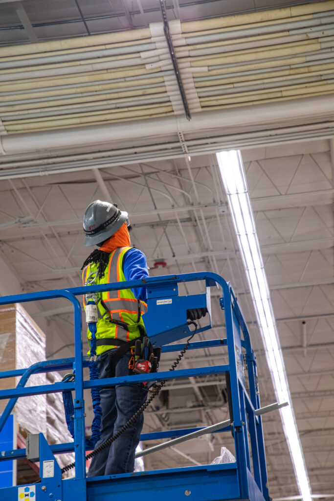 electrician on scissor lift looking up at ceiling with LED light fixtures