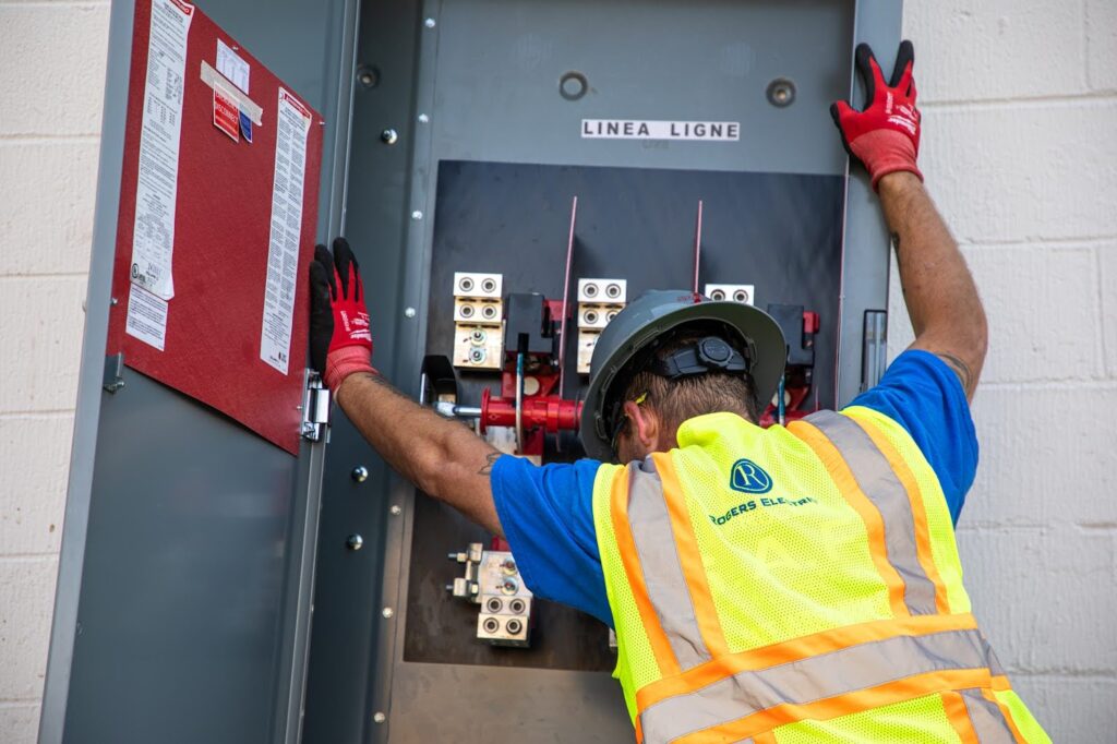 electrician leaning and lifting up an electrical panel 